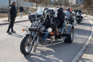 Navarcles, Spain – February 03, 2024: Front view of a black custom 3 wheel trike motorcycle with 3 passengers leading the biker exit