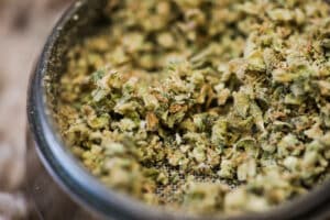 Close-up details of cannabis buds in a steel grinder.