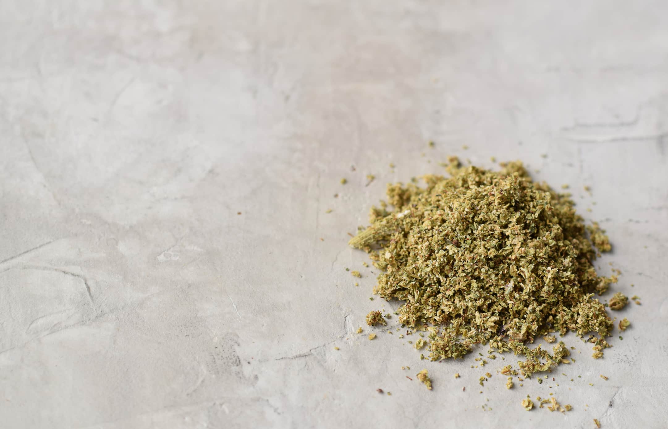 Ground weed cannabis on grey background with copy space
