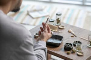 Young Asian man rolling a marijuana joint at home.