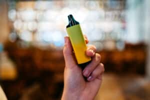 Young woman holding a vape in a bar in Malta. Close-up.