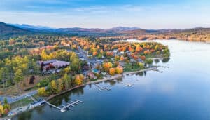 Aerial evening view of the village of Schroon Lake, NY, at sunset with brilliant fall colors, village, lake and distant Adirondack Mountains.
